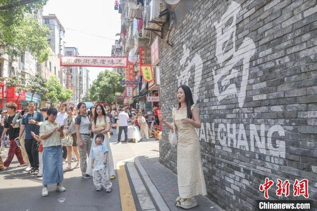 5月2日，江西南昌东湖区，游客在大士院老街的一处打卡墙前拍照。中新社记者 刘力鑫 摄