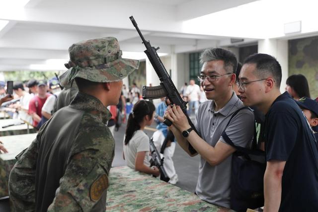 图为参观者拿起心仪的军事装备与士兵交流。(陈帅摄)