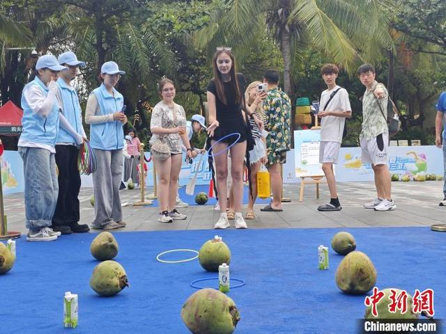 5月1日，在三亚大东海旅游区，俄罗斯游客参与椰子互动游戏。张月和 摄