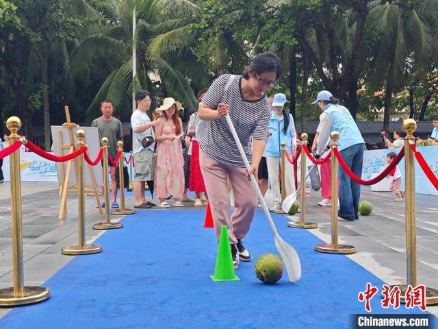 5月1日，在三亚大东海旅游区，市民游客参与椰子互动游戏。张月和 摄