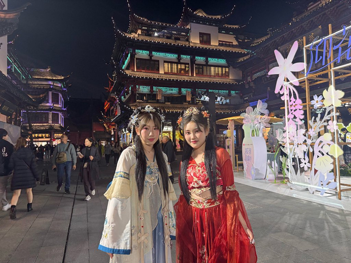 2025年仲春花朝节期间，来自日本金泽的Tomoka和Kiran在豫园商城中心广场前拍照留念。澎湃新闻记者 李菁 图