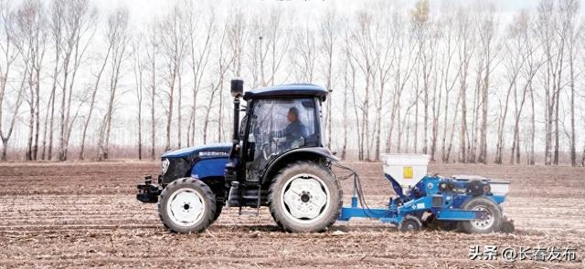 在农安县合隆镇陈家店村的一片农田里，一辆农机正在进行春耕播种作业。