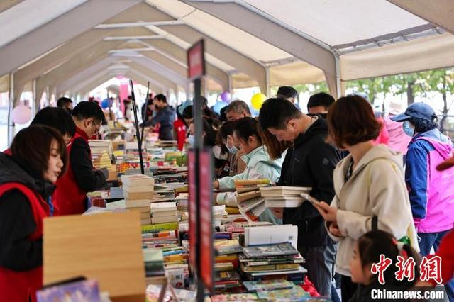图为在辽宁出版集团楼前广场读者在选购图书。中新社记者 于海洋 摄