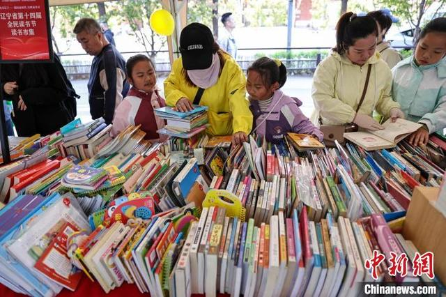 图为在辽宁出版集团楼前广场读者在选购图书。中新社记者 于海洋 摄