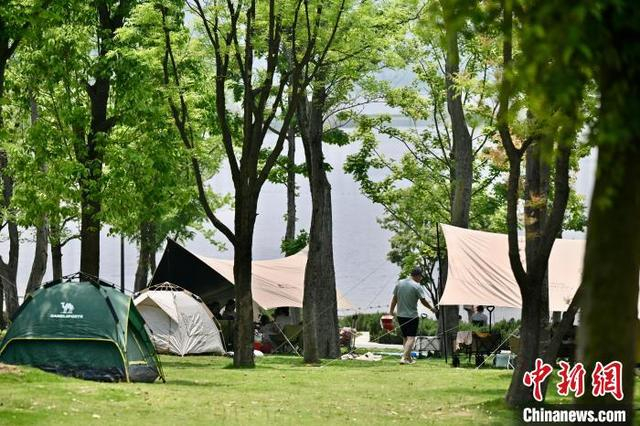 5月4日，四川成都兴隆湖人气旺，民众携带户外装备在湖畔安营扎寨，乐享“五一”露营生活。中新社记者 张浪 摄
