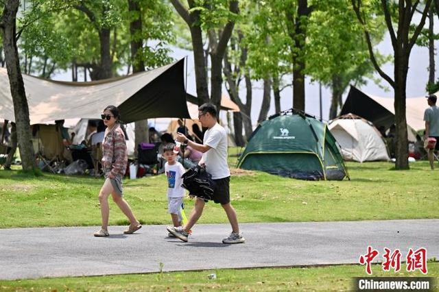 5月4日，四川成都兴隆湖人气旺，民众携带户外装备在湖畔安营扎寨，乐享“五一”露营生活。中新社记者 张浪 摄