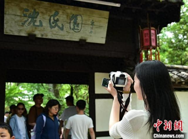“五一”假期，一名游客手持相机记录旅途风光。项菁 摄