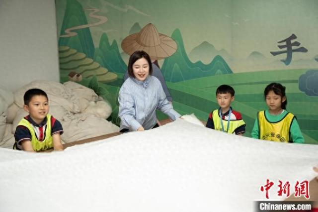 新昌县网联会会员宋莹莹向多位小朋友介绍蚕丝被制作流程。新昌县委统战部 供图