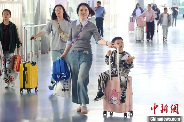 5月5日，江苏南京，旅客带着孩子在火车站出行。当日是“五一”假期最后一天，长三角铁路迎来返程客流高峰。中新社记者 泱波 摄