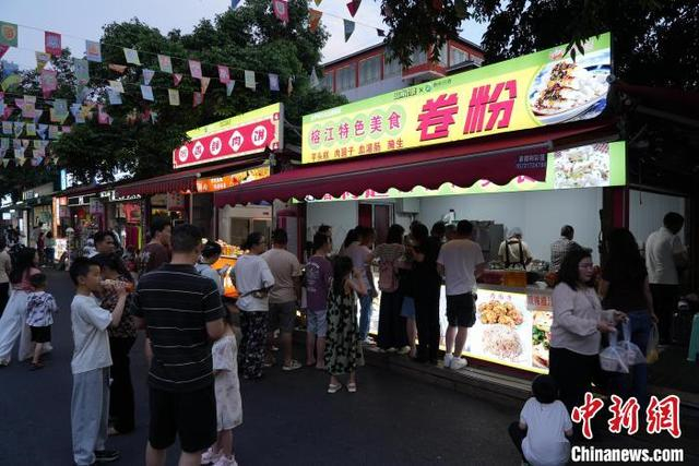 图为2025年“五一”假期期间，游客在“村超”足球场外排队购买榕江特色美食。彭震 摄