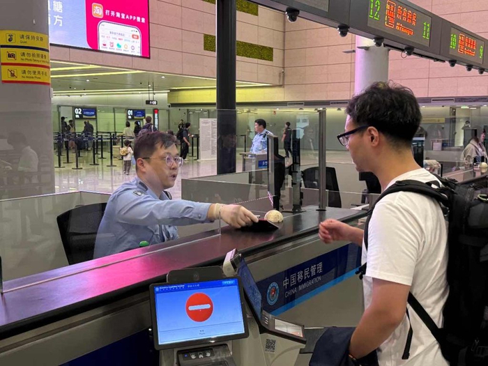 虹桥边检站民警正在为旅客办理通关手续  王伊洁 图