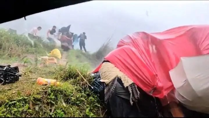 事发现场，狂风暴雨突至，剧组演员们手里的雨伞被吹翻。视频截图