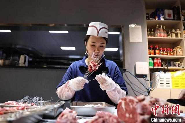 图为工作人员在穿肉串。中新社记者 于海洋 摄