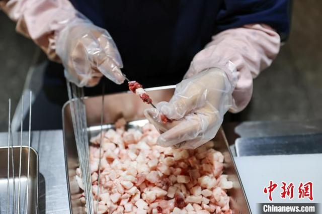 图为工作人员在穿肉串。中新社记者 于海洋 摄