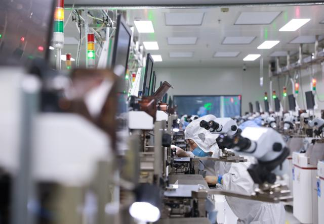 图为贵州中芯微电子科技有限公司工作人员正在操作精密仪器、加工芯片