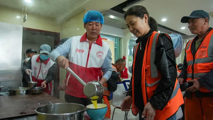 志愿者为前来用餐的环卫工人打饭 刘星辰 摄