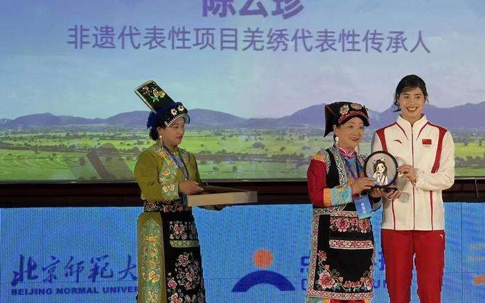 国家非遗代表性项目羌绣代表性传承人、党的二十大代表陈云珍(中)给张雨霏送上亲手做的羌绣。 新京报记者刘洋 摄