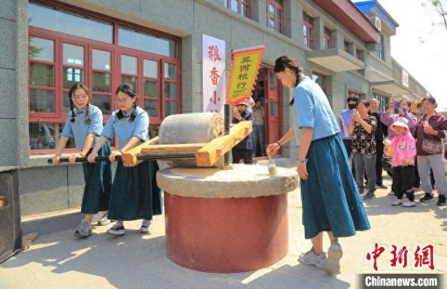 5月4日，游客在冀州老街内体验谷物研磨。 共青团冀州区委 供图