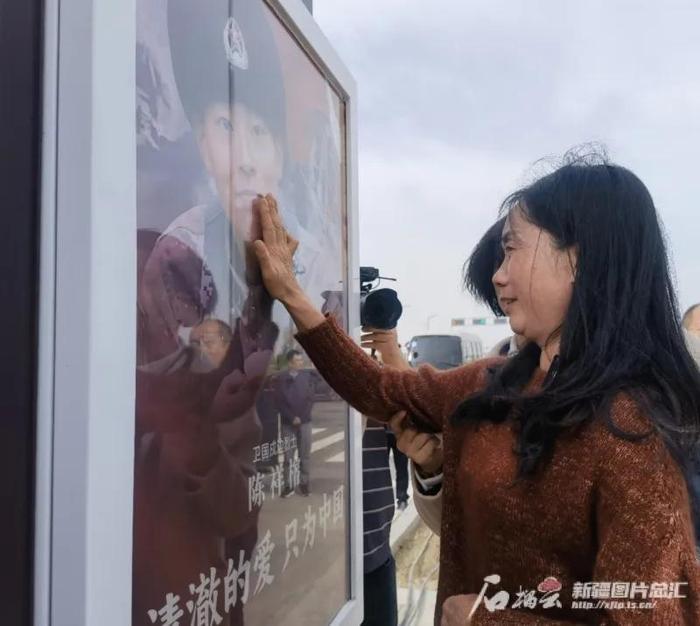 陈祥榕烈士母亲姚久穗眼含热泪轻抚路牌上儿子的照片。图源:新疆日报