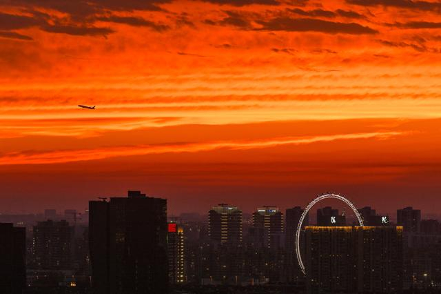 2023年7月9日，上海，一架飞机从晚霞下的锦江乐园摩天轮飞过。澎湃新闻记者 朱伟辉 资料图