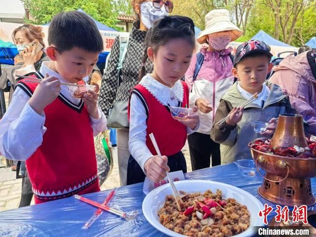 图为小朋友品尝“老八盘”菜品酸辣里脊。祁增蓓 摄