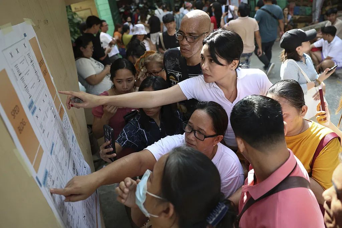 当地时间2025年5月12日，菲律宾奎松市，选民在投票站的公告栏上查找自己的名字，以便进行投票。视觉中国 图