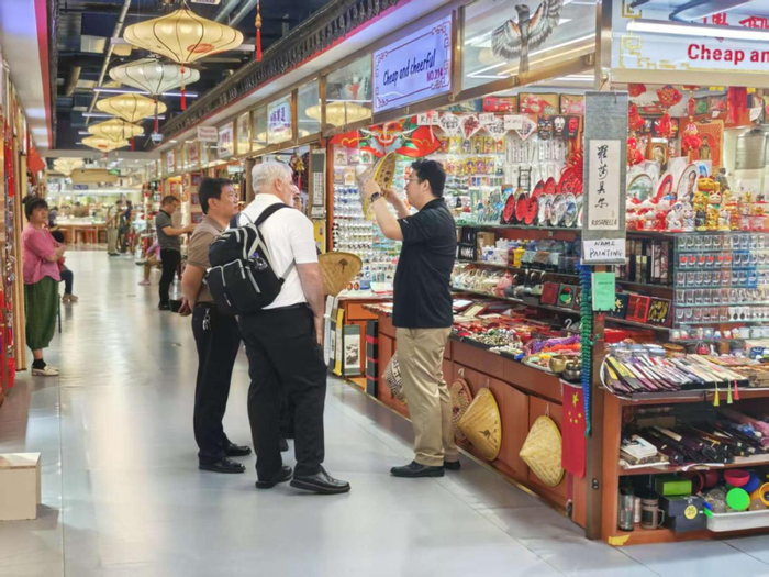 图为外国消费者正在购买竹制斗笠帽。