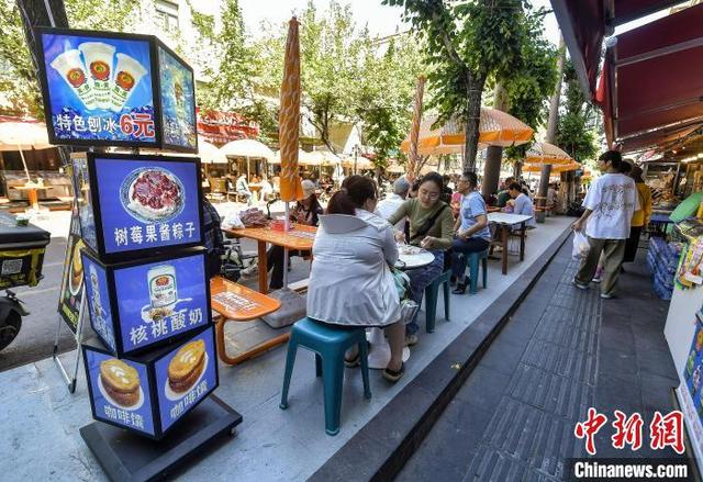 5月21日，新疆乌鲁木齐市和田二街，游客在街头品尝美食。中新社记者 刘新 摄