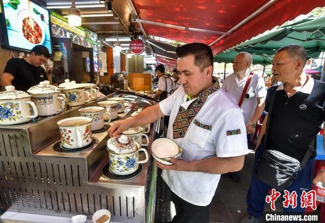 5月21日，新疆乌鲁木齐市和田二街，新疆美食——缸缸肉吸引游客。中新社记者 刘新 摄