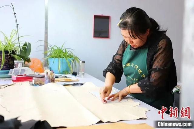 图为工人们在制作皮衣。中新社记者 张林虎 摄