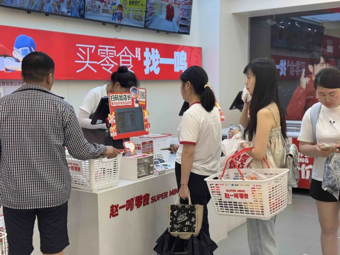 零食量贩店内顾客正在排队买单。