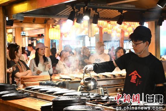 5月24日晚，游客在敦煌夜市沙州食驿选购品尝美食。张晓亮 摄