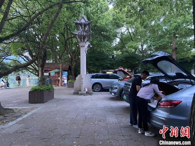 近日，游客在杭州西湖畔整理后备箱。 林波 摄