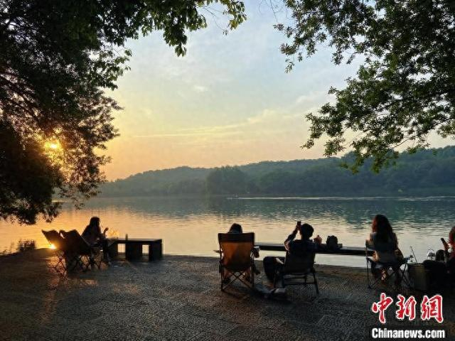 近日，“夜泊”游客在杭州西湖畔看日出。 林波 摄