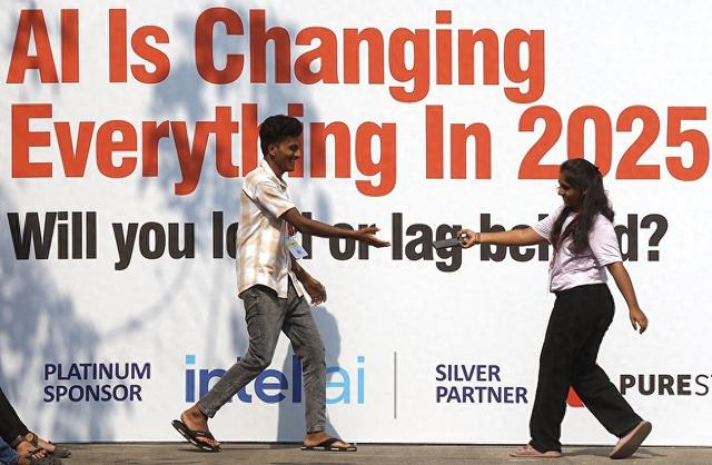 3月26日，2025人工智能开发者大会与博览会在印度班加罗尔举行。图为路人走过博览会宣传牌。（视觉中国）