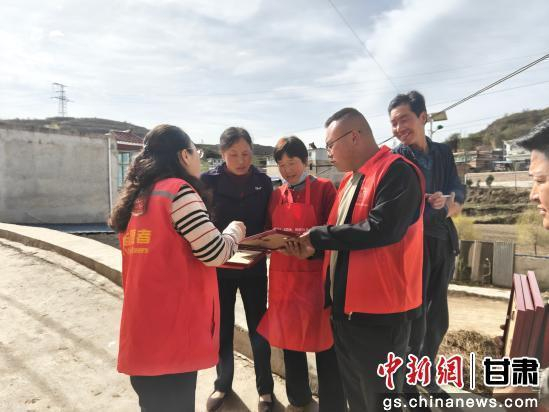 图为志愿者给群众发放印刷装裱后的照片。