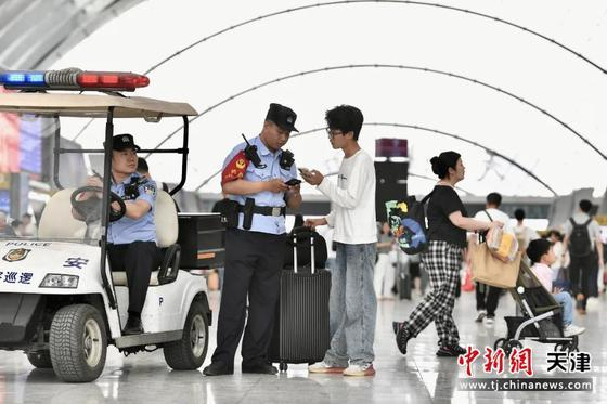 图为天津西站派出所民警正在帮助旅客查看乘车信息。（北京铁路公安局天津公安处供图）
