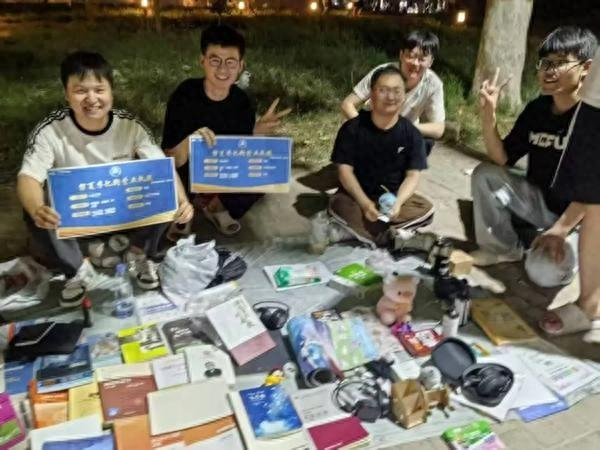河南师范大学毕业生在摊位前展示“营业执照”。李梦飞/摄
