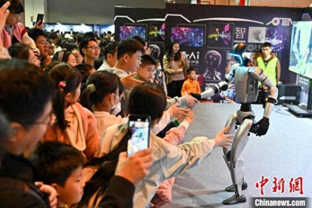 4月5日，“AI智能机器人科普展”在广州南丰国际会展中心开展，现场观众与一款人形机器人互动。 中新社记者 陈骥旻 摄