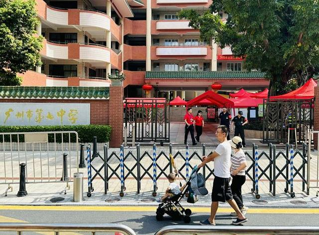 一对年轻夫妇推着婴儿车走过广州市第七中学门口，当时考场内正在进行语文科考试。中青报·中青网记者 林洁/摄