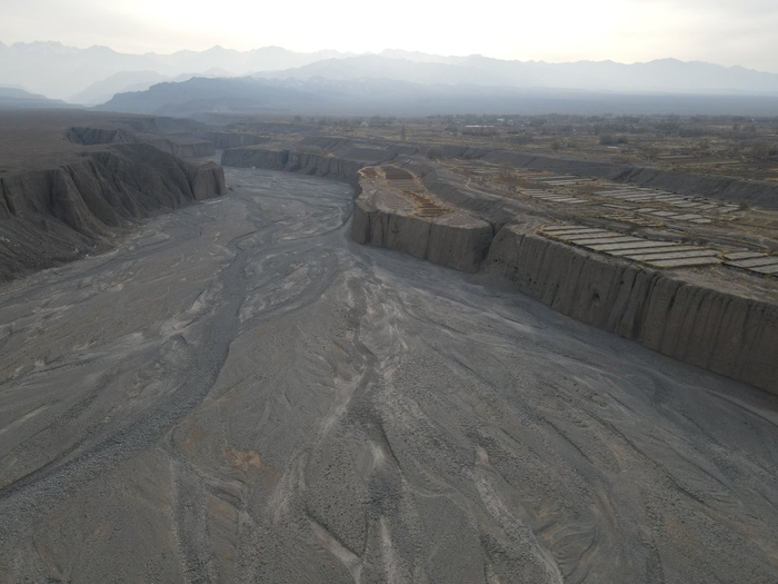 图3 洪水河巨堑及其西岸耕地村庄，崖壁可见明清洞子渠水平导洞洞口，嘉峪关市融媒体中心外宣中心主任高翔摄。
