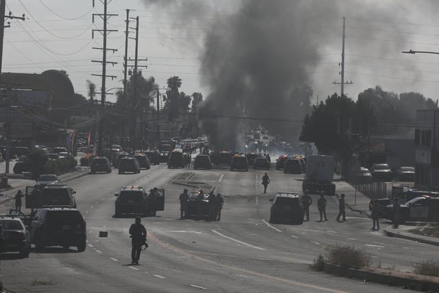 6月7日，在美国加州洛杉矶县，示威民众与警方对峙现场冒出浓烟。新华社发（邱晨摄）