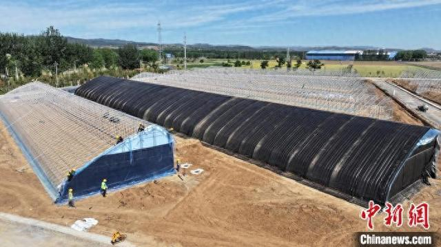 工人们穿梭其间，进行温室主体搭建、保温覆盖安装、厂区工程施工及露天蔬菜种植等作业。 牛刚 摄