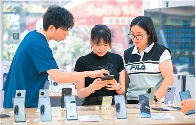 广西壮族自治区梧州市积极落实消费品购新补贴政策,满足市民消费需求。图为梧州市长洲区一大型购物商场,顾客在挑选新款手机。