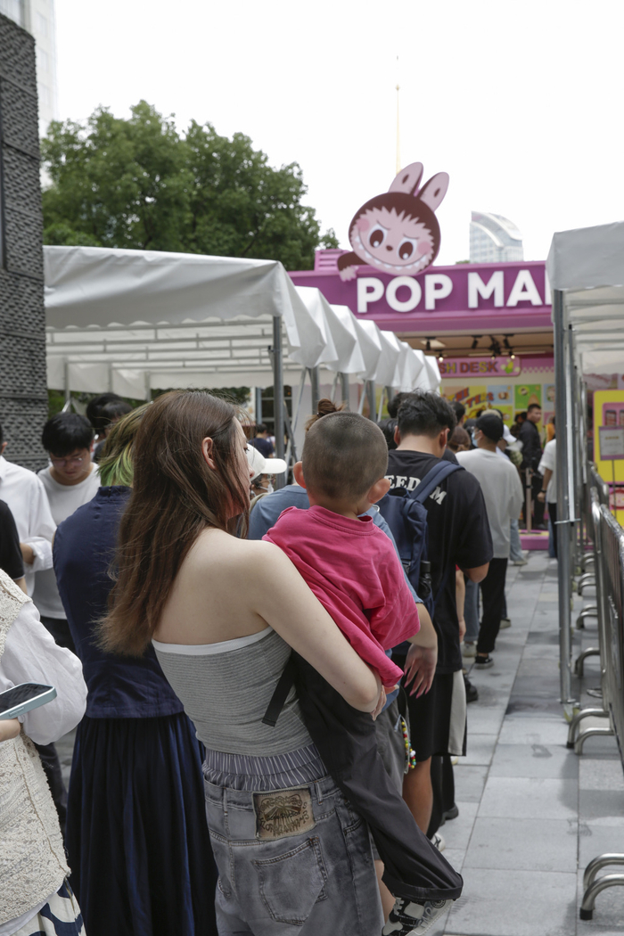 2025年6月13日，一位母亲抱着孩子正在排队入店。澎湃新闻记者 吴栋 图