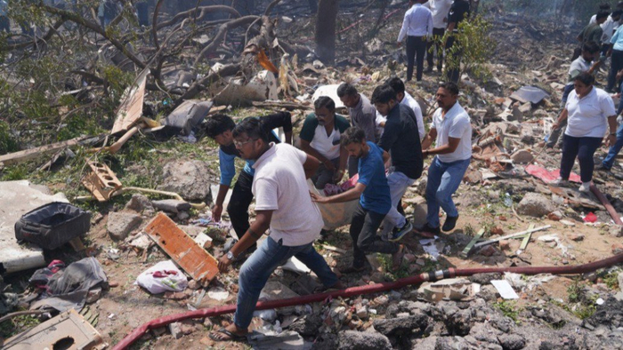 6月12日，在印度古吉拉特邦艾哈迈达巴德，人们在客机失事现场运送一遇难者遗体。新华社 图