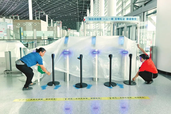 6月12日，在海口新海港候船大厅，工作人员正在使用防水袋将闸机包裹起来。石中华/摄