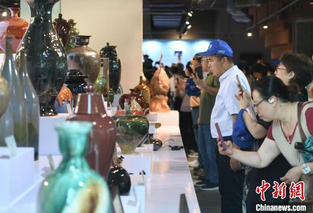 图为展出现场的重庆荣昌陶作品吸引参观者驻足欣赏、拍照。中新社记者 周毅 摄 
