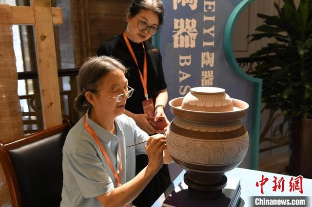 图为展览现场，工作人员对荣昌陶器进行剔刻吸引参观者眼球。中新社记者 周毅 摄 