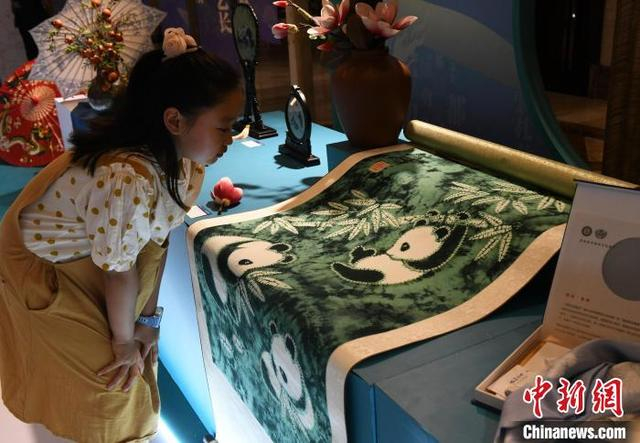 图为展览现场，自贡扎染技艺作品《熊猫家园》吸引小朋友一探究竟。中新社记者 周毅 摄 
